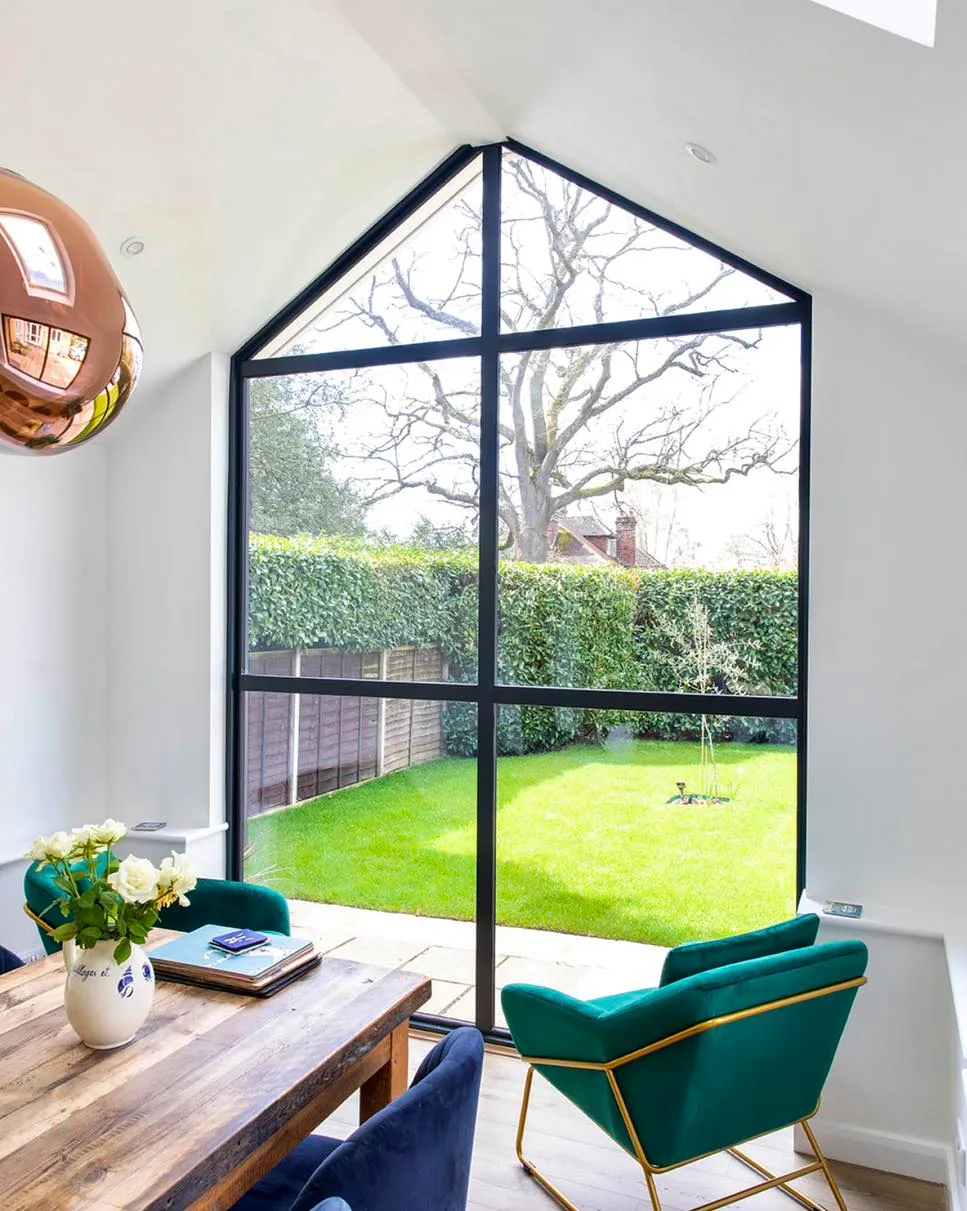 A room with a table, chairs, and a large window.