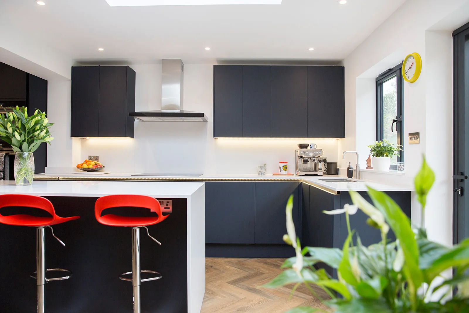 A modern kitchen with black cabinets and red stools.