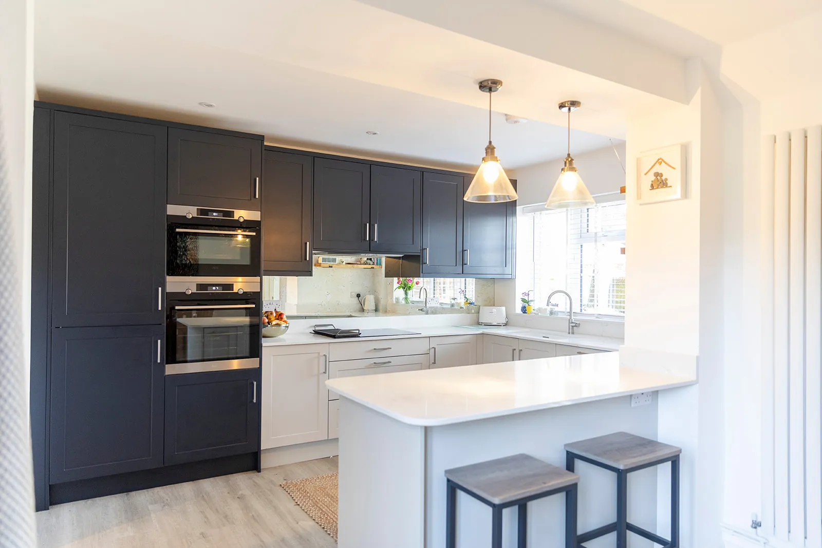 A kitchen with a stove, oven, sink and two stools.